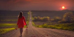 A solitary woman walking away on a path, symbolizing the difficult decision to move on after infidelity.